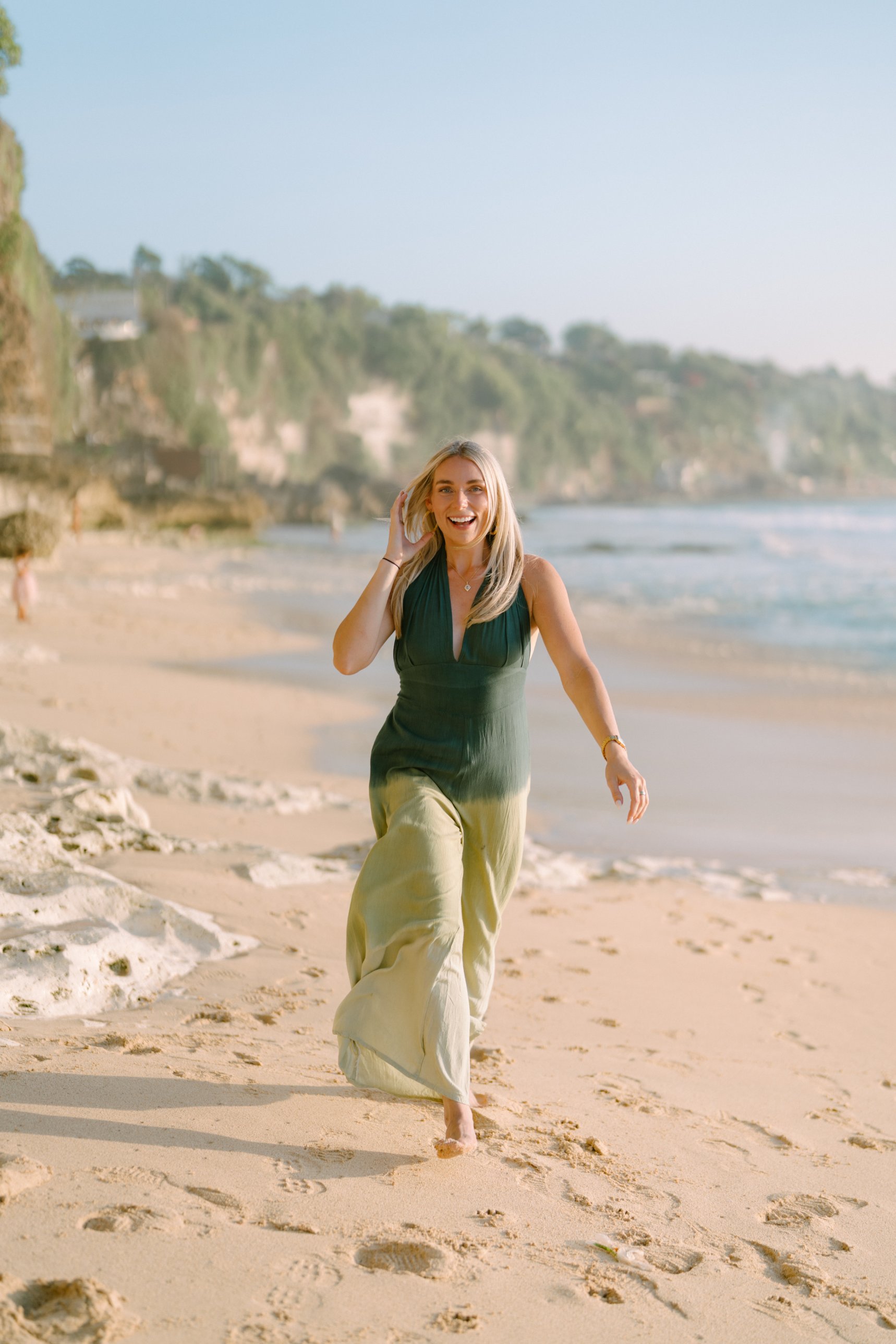 Hannah laughing as she walks along the beach at golden hour