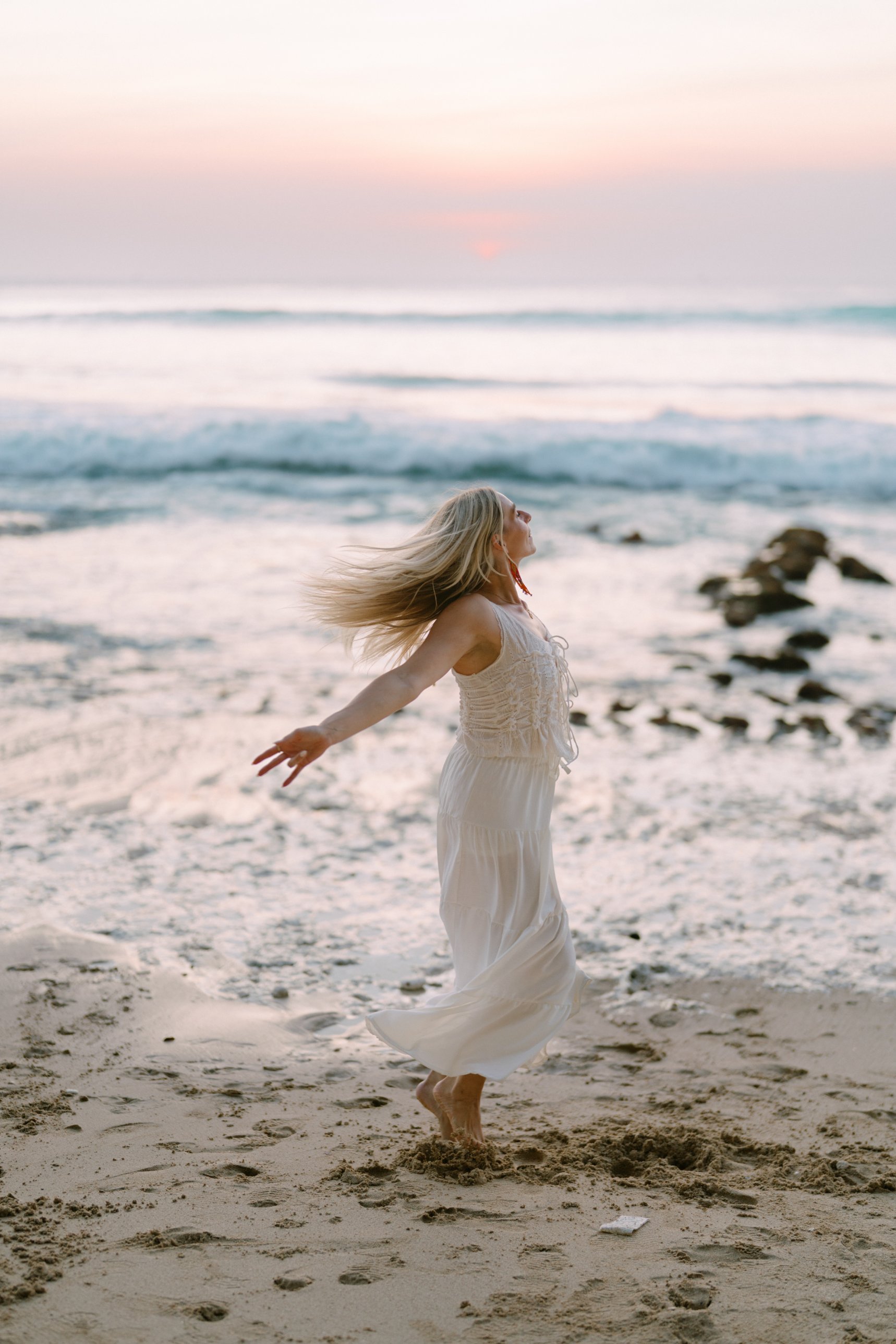 Hannah twirling on the beach at sunset